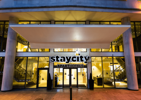 The exterior of staycity aparthotel. A glass frontage and black staycity sign