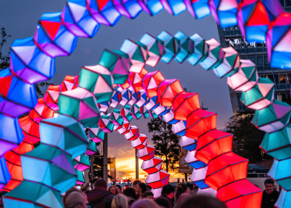 Multi coloured light installation in arch ways with people walking through