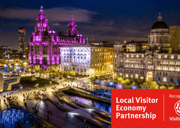 Liverpool Pier Head lit up with different coloured lights.